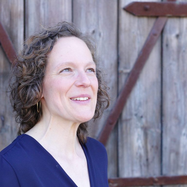 Jennifer Bosch, zertifizierte Mediatorin und systemischer Coach, lächelnd vor rustikaler Holztür