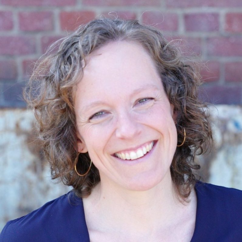 Jennifer Bosch, Business Coach für Führungskräfte und Teams, lachend vor Backsteinwand 