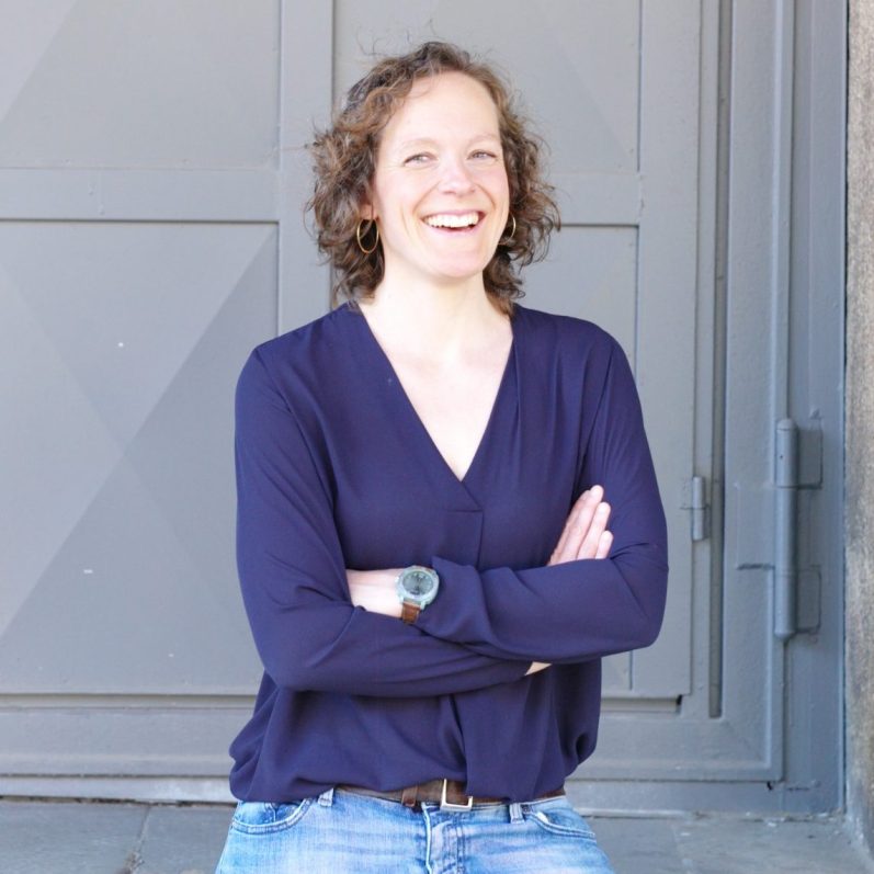 Jennifer Bosch – Business Coach für Führungskräfte & Teams, lächelnd vor moderner grauer Tür