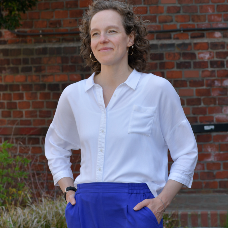 Jennifer Bosch, Business Coach für Führungskräfte und Teams, lachend vor Backsteinwand 