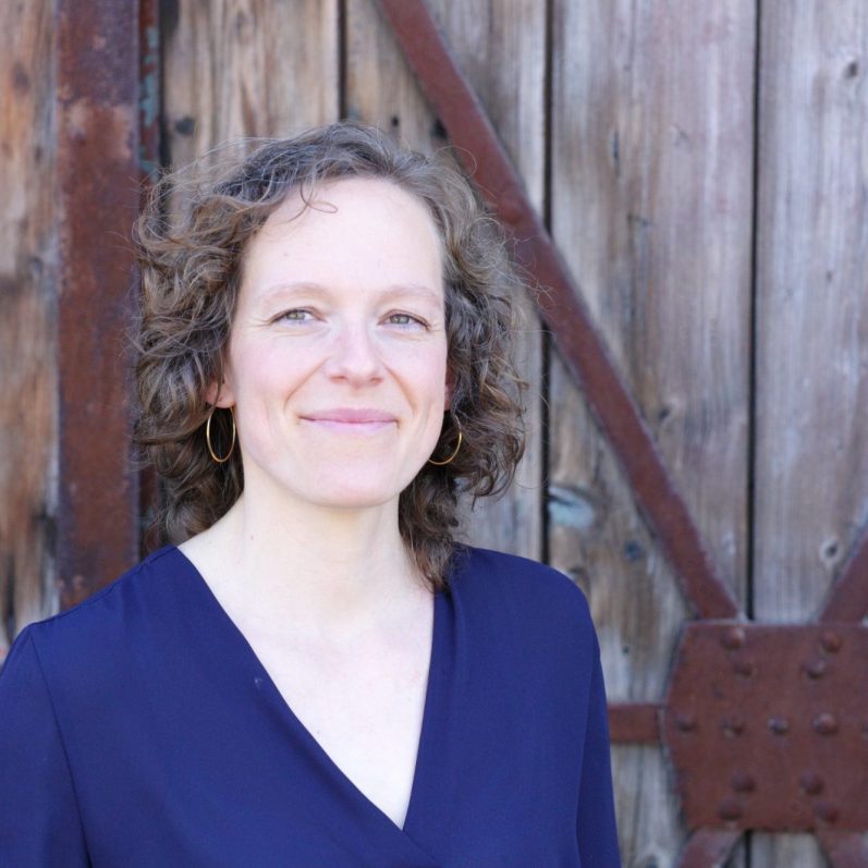 Jennifer Bosch, Coach für Einzelcoaching, Führungskräfteentwicklung und Teamentwicklung, vor einer rustikalen Holztür